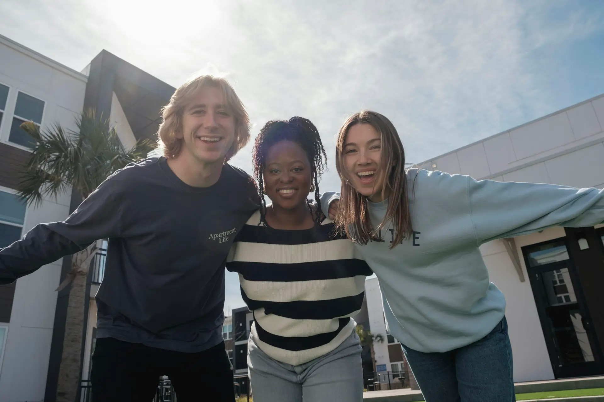 Three smiling friends, arms around each other